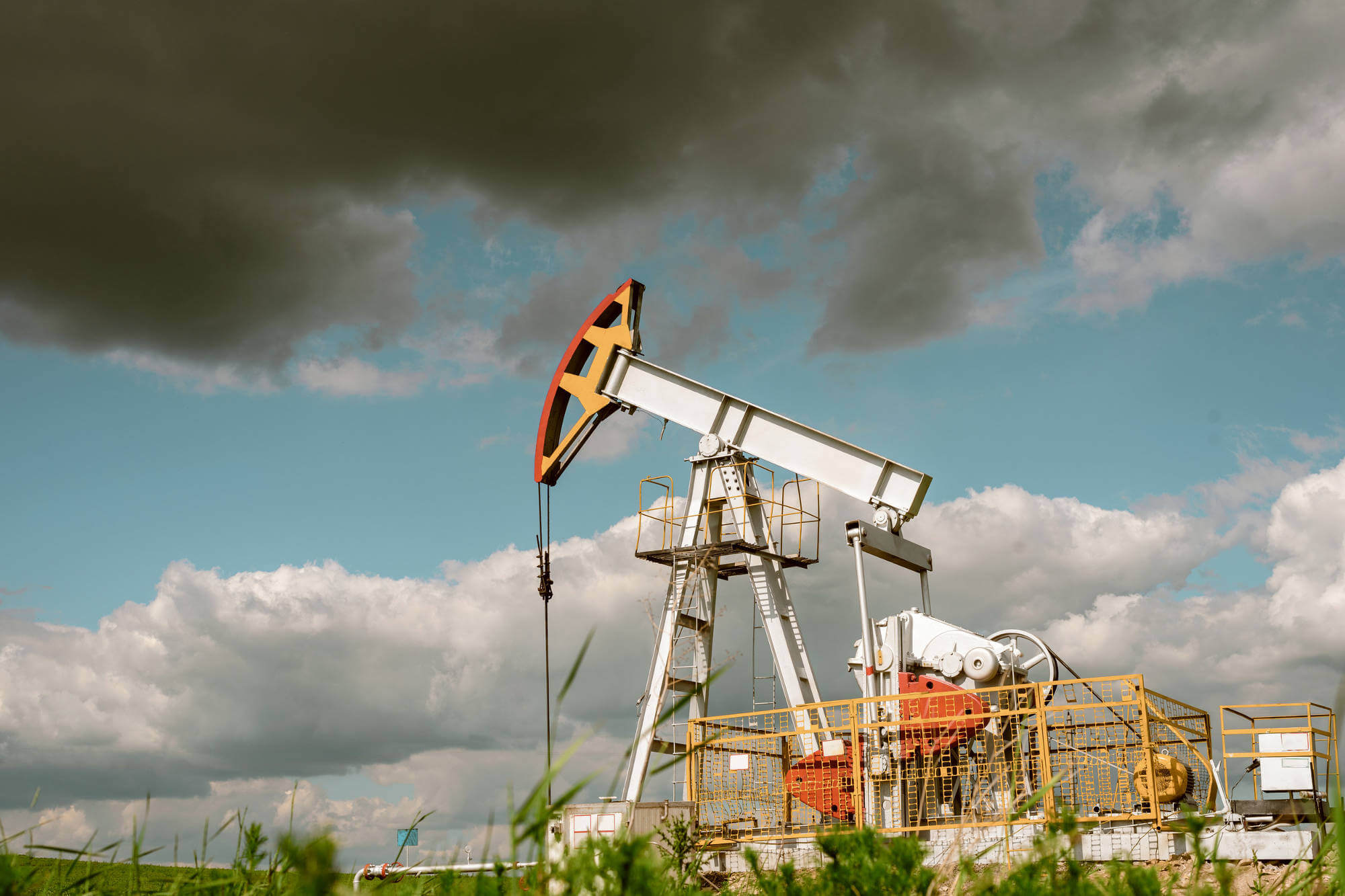 Pump rocking for oil and associated gas in the field against the cloud sky.